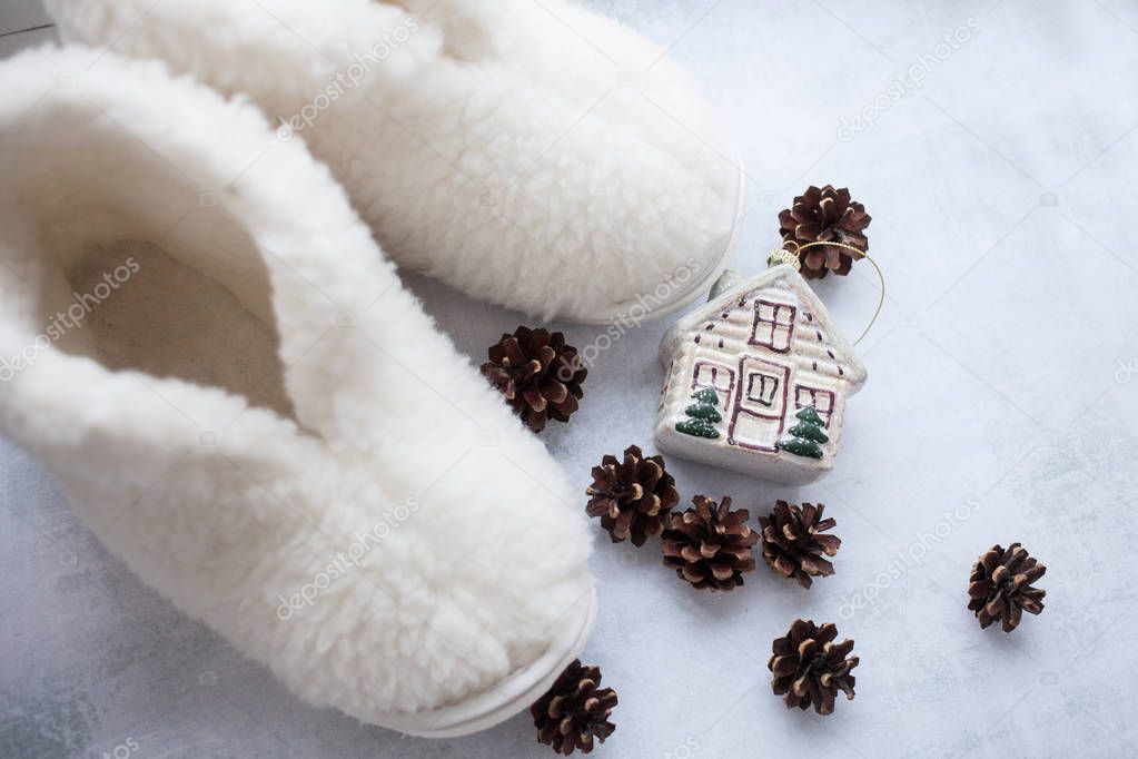 a pair of cozy white fur slippers with cones and a house