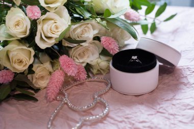 nişan yüzüğü bir pembe Kağıt arka plan ve beyaz gül ve pembe lagurus oluşan bir buket ile yuvarlak beyaz kutu içinde yukarı kapatın