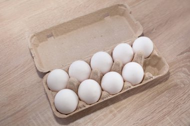 On dakika içinde ahşap masa üzerinde bir yumurta kartonu yerine dokuz beyaz yumurta. Ekonomi ve finans, shrinkflation kavramı. Paskalya. üstten görünüm