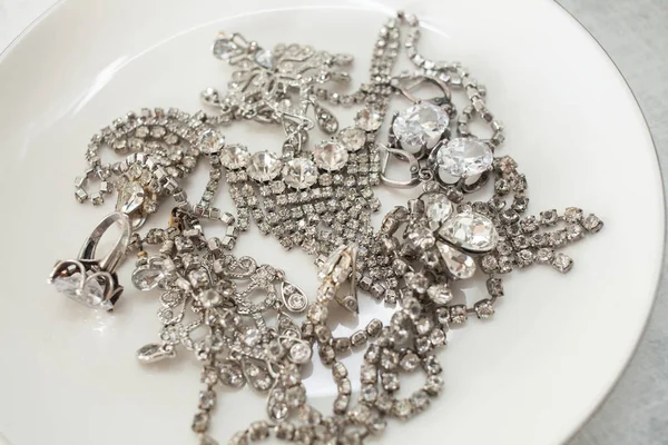Πολλές αφρωδών κοσμήματα σε ένα λευκό πιάτο την έννοια της πολυτέλειας ζωής, πλούτο, αίγλη, μόδα και Γάμοι — Φωτογραφία Αρχείου