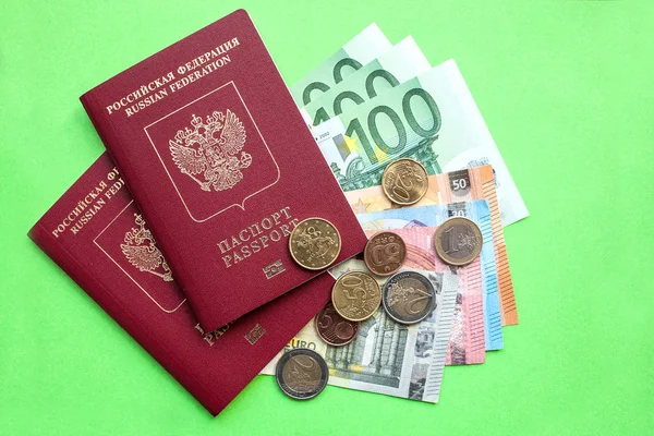 Dva ruské zahraniční pasy a euro bankovek různých nominálních hodnot a eurocentů na zeleném pozadí — Stock fotografie