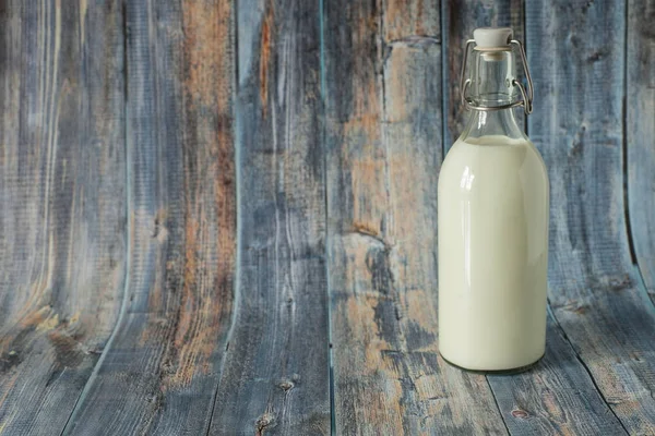 Frische Milch zum Frühstück in einer Glasflasche auf einem hölzernen Hintergrund in Blautönen — Stockfoto