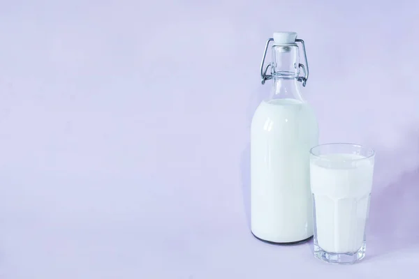 Leche fresca para el desayuno en una botella de vidrio y un vaso de leche sobre fondo lavanda —  Fotos de Stock