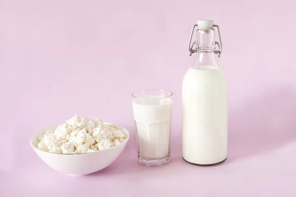 Taze süzme peynir ve süt kahvaltı için bir cam şişe ve bir bardak süt çerçeve merkezinde pembe bir arka plan — Stok fotoğraf