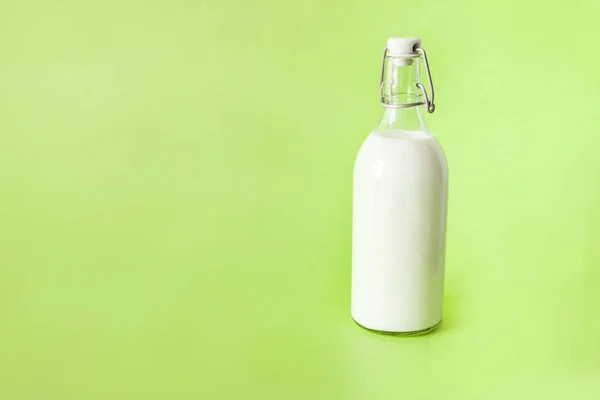 Melk in een fles op een groene achtergrond — Stockfoto