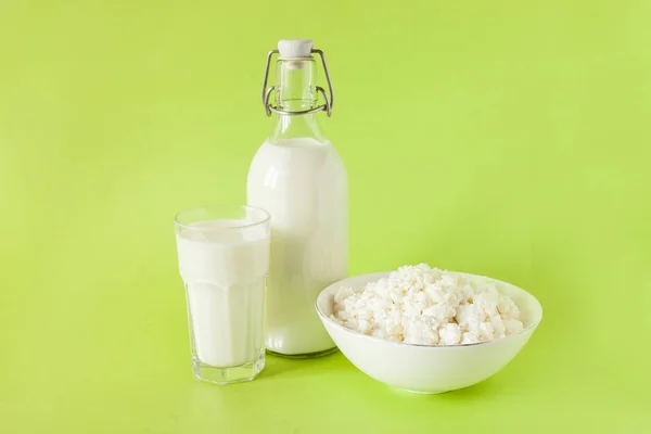 Latte in una bottiglia fiocchi di latte e un bicchiere di latte su uno sfondo verde — Foto Stock