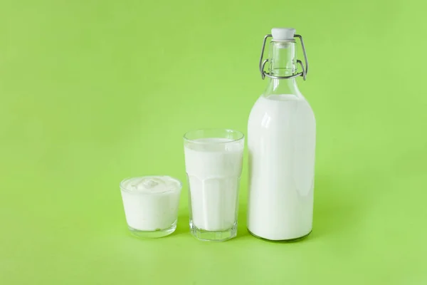 Kefir mleka i śmietana są w rzędzie na zielonym tle. Świeże produkty mleczne na śniadanie — Zdjęcie stockowe