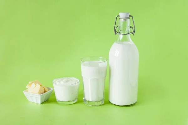 Milch Kefir saure Sahne und Butter sind in einer Reihe auf grünem Hintergrund. frische Milchprodukte zum Frühstück — Stockfoto