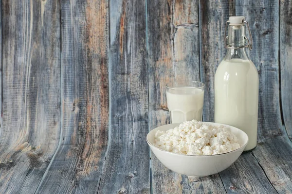 Latte in una bottiglia fiocchi di latte e un bicchiere di latte su uno spazio di copia di sfondo in legno — Foto Stock