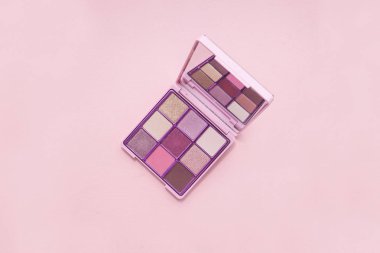 top view Palette of pink cosmetic make up with a mirror on pink background, colorful shadows minimalism, on light pink background clipart