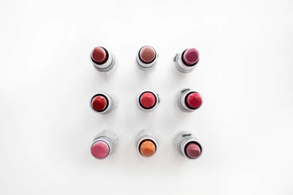 Lipstick in different natural colors arranged in a square on a white background. Top view — Stock Photo, Image