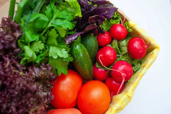 Komkommers, tomaten, radijsjes, sla, basilicum, peterselie in een doosje met een geel servet. ruimte voor tekst — Stockfoto