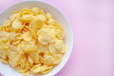 Pembe bir backgroud üzerinde beyaz bir kase mısır gevreği kuru kahvaltı. metin alanı