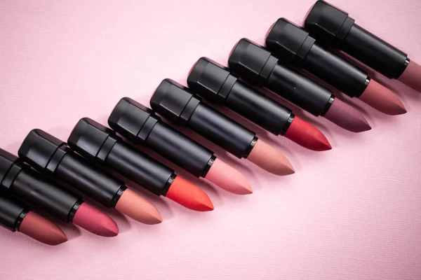 Lipstick in different natural colors on a pink background. Top view with selective focus — Stock Photo, Image