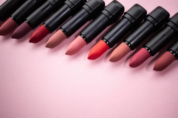 Lipstick in different natural colors in a row at the bottom of the picture in a row diagonally on the top of the picture on a pink background. selective focus copy space — Stock Photo, Image