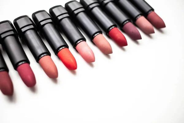 Lipstick in different natural colors on a white background. Top view with selective focus — Stock Photo, Image