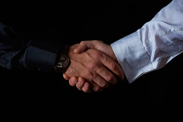 Dois homens de negócios do sexo masculino em preto e branco camisa apertar as mãos, fundo preto, estúdio de tiro — Fotografia de Stock