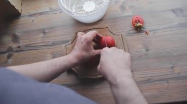 Bir erkek sebzeleri yıkar, temizler ve keser.