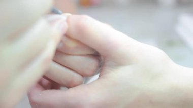 Manikür ustası müşterilerin elindeki jöle cilasını keser.