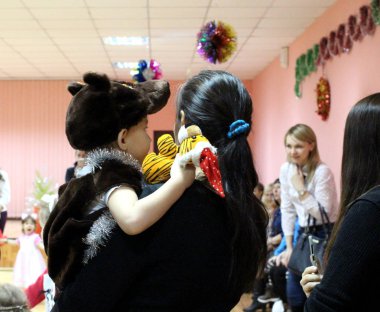 bir küçük çocuk çocuk komik bir fantezi elbise yeni yıl tatil stand geri tutan anne