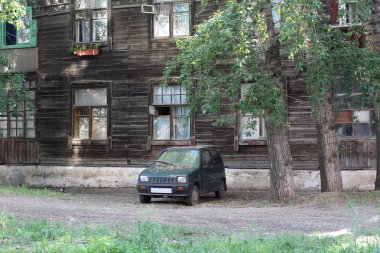 Eski ahşap blok daireler plakalar ile Windows duvarla çürük sundurma bahçesinde arabada desenli