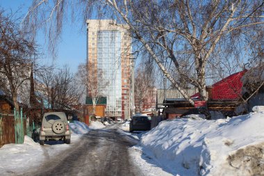 park etmiş araba ile Novosibirsk Parkhomenko sokakta baharda özel evlerin yakınında kirli geçit şehir yüksek katlı bina yol açar