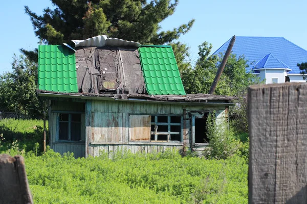 旧木毁的房子被遗弃在草地上 窗户上有一个美丽的图案俄罗斯西伯利亚村 — 图库照片
