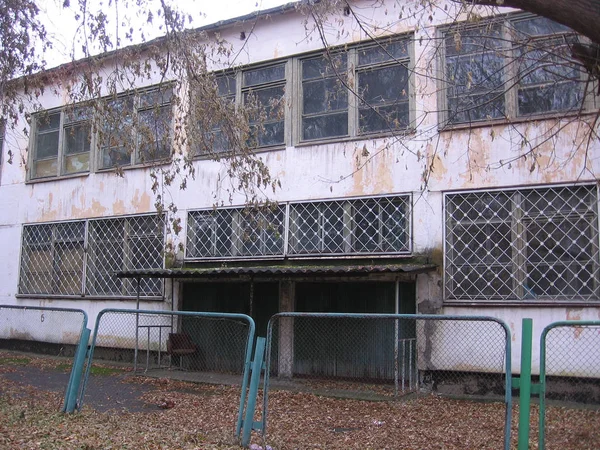 一所废弃的学校的旧建筑在倒塌的栅栏后面 在秋天闲置中被清空 — 图库照片