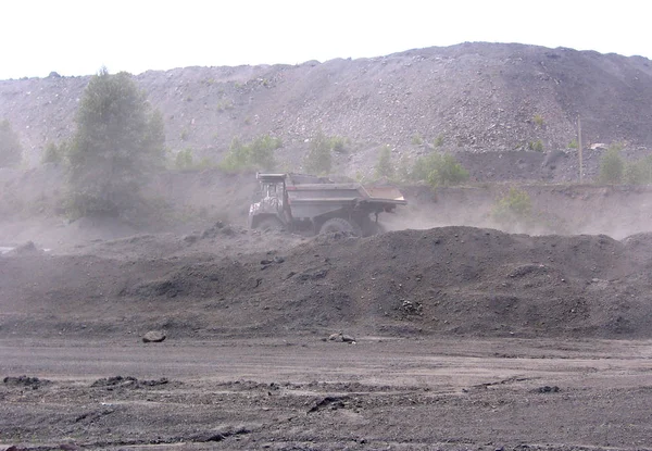 industrial mining at coal pit through the dust goes BelAZ truck loaded with coal and crushed stone