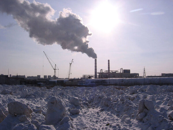 industrial landscape of a production factory on a vacant lot in winter under the snow factory pipes smoke pollute the air