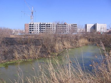 Bataklık sanayi bölgesindeki pis bir gecekondunun yanına bir apartman inşa ediliyor.