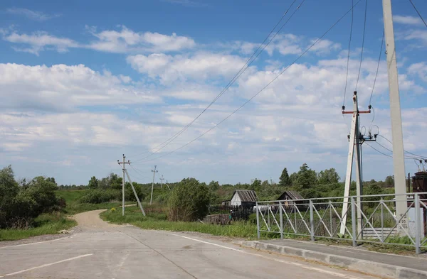 住宅への未舗装の道路近くの村のための高電圧線の電柱上の電気 — ストック写真