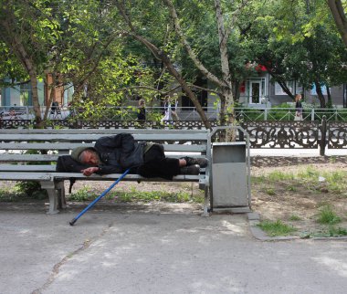 Rusya, Novosibirsk 30.06.2019: evsiz sarhoş bir adam sokak serserisindeki bankta sarhoş geziyor