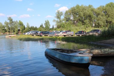 Rusya, Novosibirsk, 07.07.2020: nehir kıyısındaki araçlar için park alanı yakınındaki suya inen kayıklar.