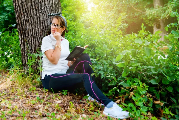 森の中で本を読んでいる若い女性 幸せな女性の笑顔 — ストック写真