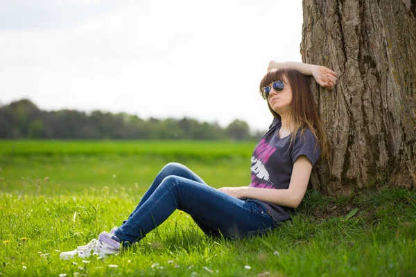 Unbekümmerte Frau Sitzt Auf Grünem Gras Und Lehnt Baum — Stockfoto