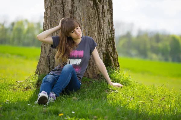 Beztroski Kobieta Siedzi Zielonej Trawie Opierając Się Drzewo — Zdjęcie stockowe