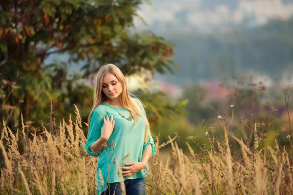 beautiful young woman with long hair posing in summer field