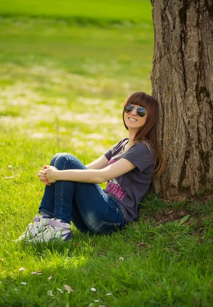 Unbekümmerte Frau Sitzt Auf Grünem Gras Und Lehnt Baum — Stockfoto