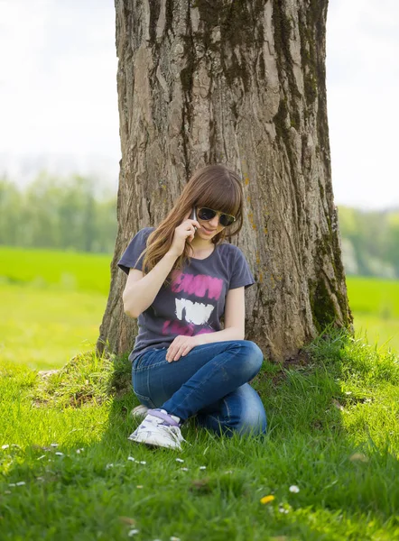 Frau Sitzt Auf Grünem Gras Lehnt Baum Und Telefoniert — Stockfoto