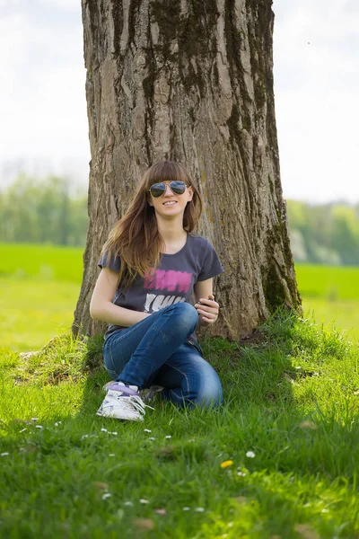 Unbekümmerte Frau Sitzt Auf Grünem Gras Und Lehnt Baum — Stockfoto