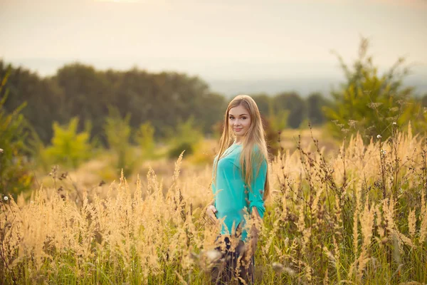 beautiful young woman with long hair posing in summer field