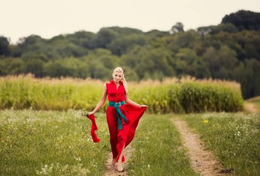 yeşil yaz alanında poz papatya çiçeği ile kırmızı elbiseli güzel sarışın kadın