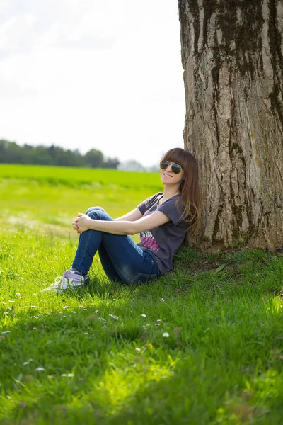 Beztroski Kobieta Siedzi Zielonej Trawie Opierając Się Drzewo — Zdjęcie stockowe