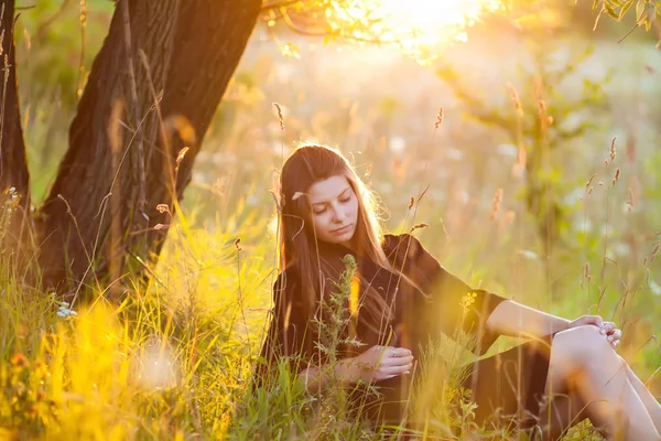 夏の芝生での木の近くの草の上に横たわる屈託のない若い女性 — ストック写真