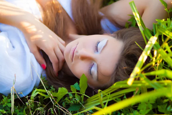 夏の芝生で草の上に横たわる屈託のない若い女性 — ストック写真