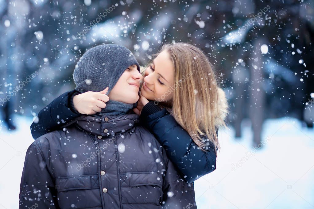 happy young couple kissing in winter park 