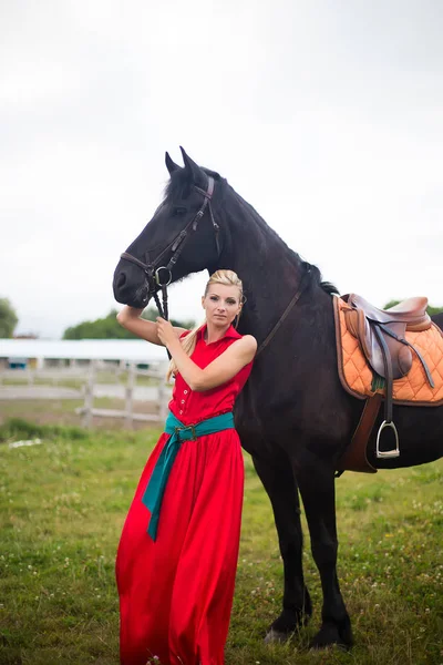 Modische blonde Frau, die an sonnigen Tagen ein Pferd reitet. lange Haare. — Stockfoto