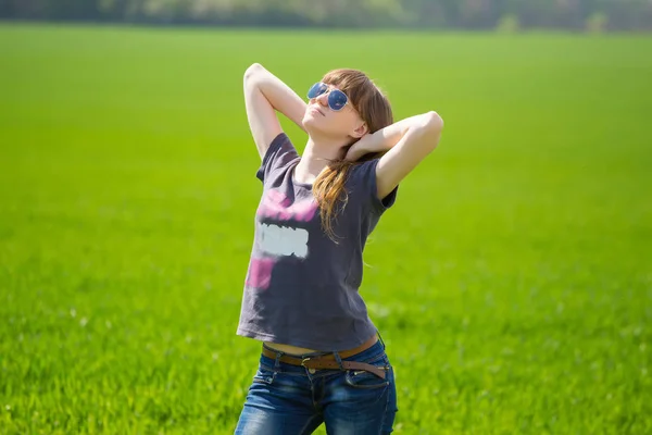 Счастливая женщина, стоящая на зеленом поле — стоковое фото