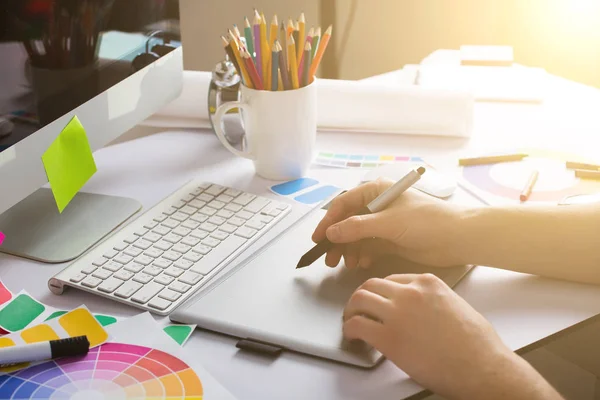 Young Handsome Graphic designer using graphics tablet to do his work at desk